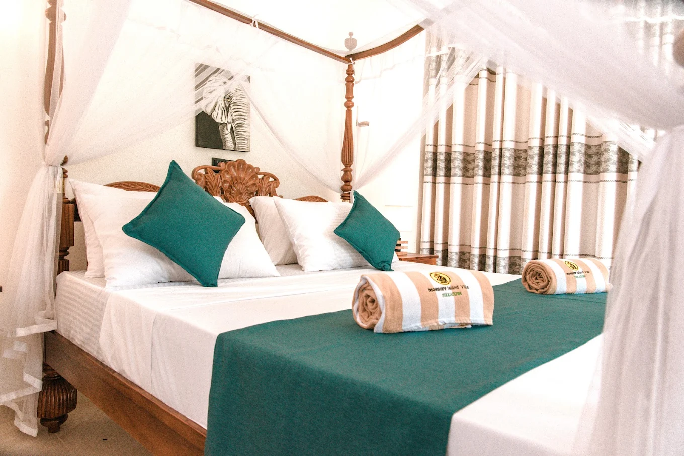 Double bed with teal cushions and fresh towels at Monkey Island Villa
